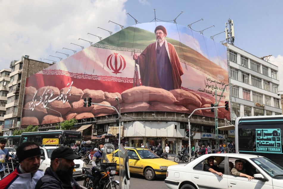 Pendler fahren in Teheran an einer großen Plakatwand vorbei, auf der der oberste Führer Ayatollah Mojtaba Khamenei abgebildet ist.