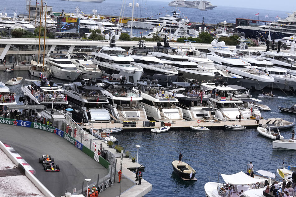 Links unten rast Max Verstappen über die Rennstrecke, daneben liegen im Hafen von Monaco jede Menge Jachten von Stars und Sternchen.