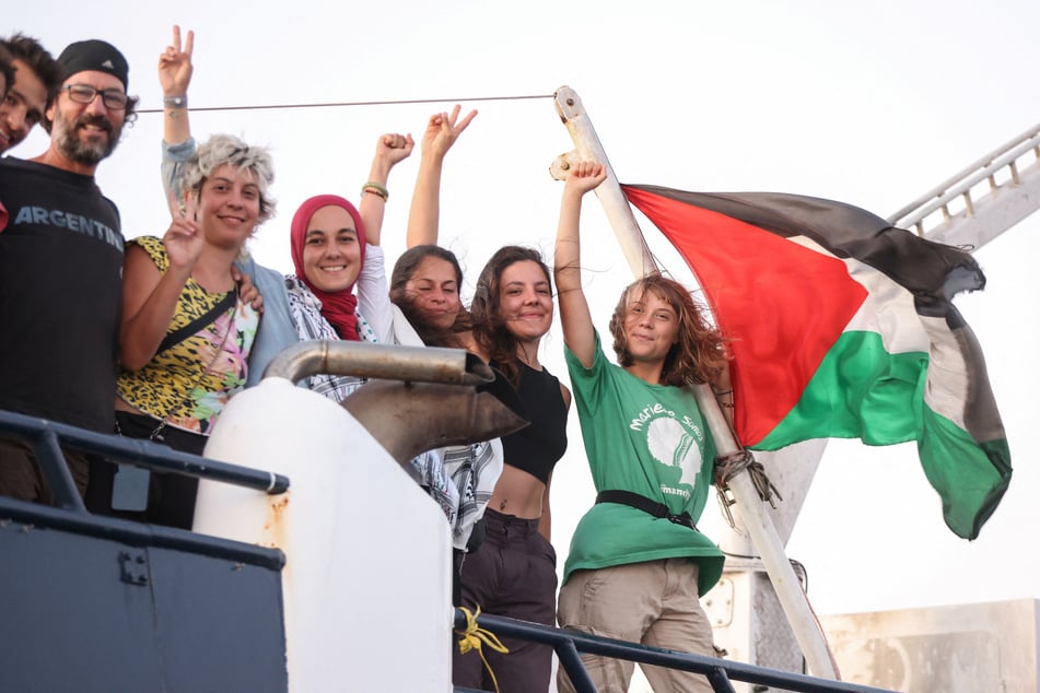 Greta Thunberg and other crew members flash victory signs from their ship, part of the Global Sumud Flotilla aiming to break Israel's blockade of Gaza, as they sail off Greece's Crete island on September 25, 2025.