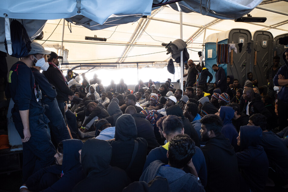 Aus dem Mittelmeer gerettete Flüchtlinge sitzen an Deck des deutschen Seenotrettungsschiffes "Humanity 1".