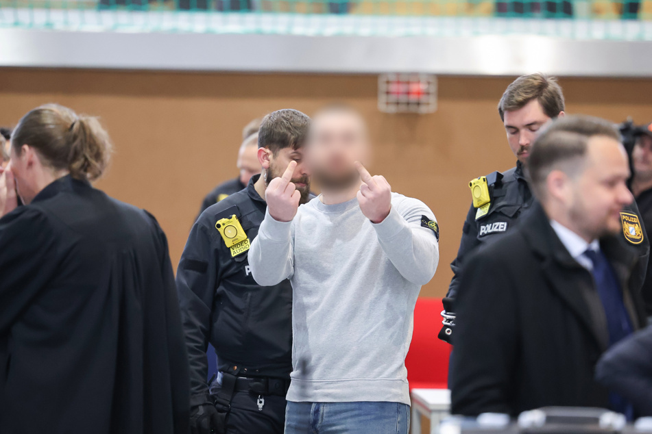 Einer der Angeklagten zeigt zwei Mittelfinger. Für den Prozess am Landgericht Bamberg sind mehr als 70 Verhandlungstage geplant.