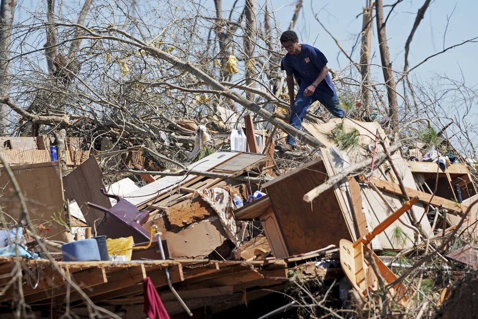 Ein Jugendlicher kletterte nach einem Tornado auf einen Berg von Trümmern, um bei der Bergung von Gegenständen zu helfen, die durch den Tornado in Tylertown nicht zerstört wurden.