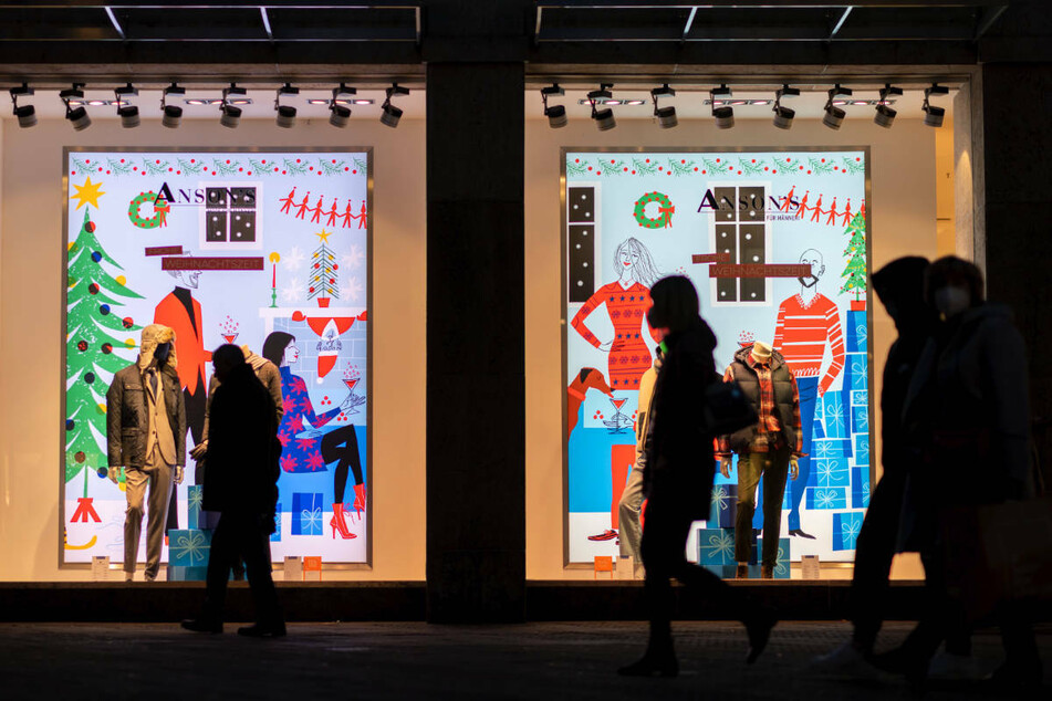Passanten gehen an weihnachtlich geschmückten Schaufenstern eines Kaufhauses vorbei. Durch eine Ausweitung der 2G-Regel befürchtet der Einzelhandel in Brandenburg einen Einbruch beim wichtigen Weihnachtsgeschäft. (Symbolfoto)