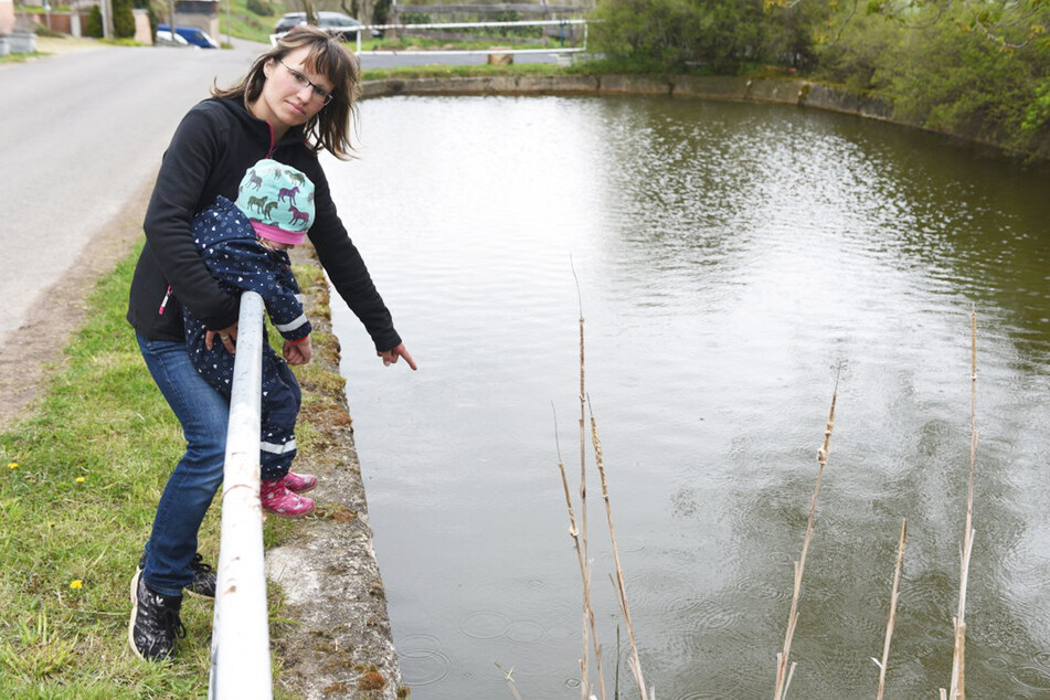 Melanie Seidel und ihre Tochter zeigen auf die Stelle im Teich, an der sie den Hund fanden.