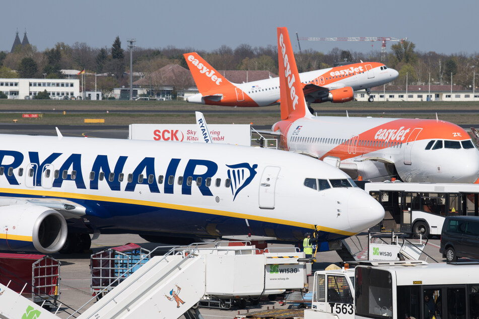 Flugzeuge der Gesellschaften Ryanair und Easyjet stehen auf dem Flughafen Tegel, während im Hintergrund eine Maschine gerade startet.