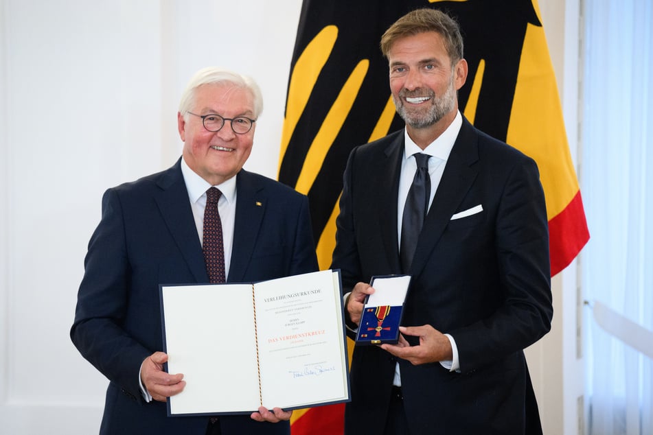 Der Bundespräsident Frank-Walter Steinmeier (68) und der Kult-Trainer mit dem Bundesverdienstorden in der Hand strahlen um die Wette.