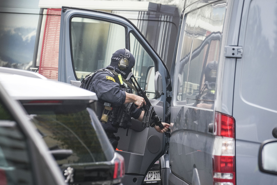 Ein Mitarbeiter des Sondereinsatz-Kommandos der Polizei holt in einer abgesperrten Straße im Frankfurter Gallusviertel seine Waffe aus dem Fahrzeug.