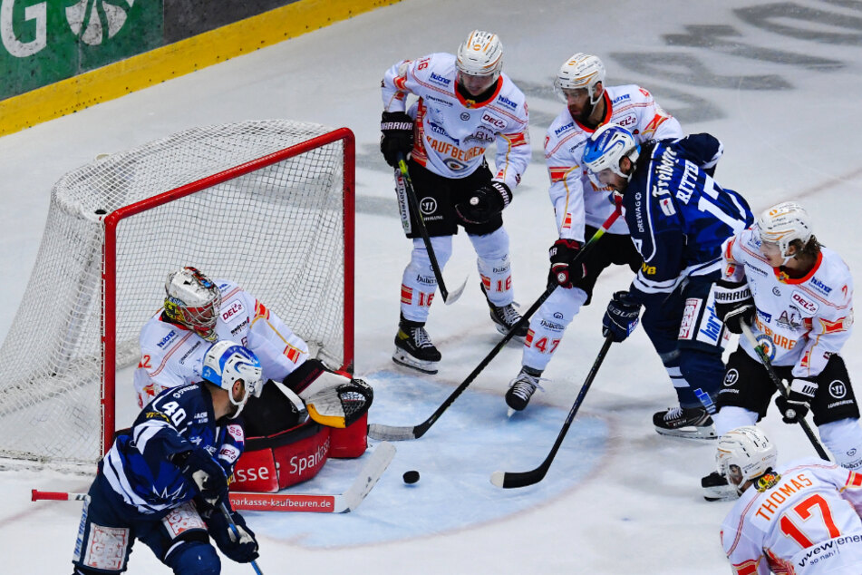 Nick Huard (l.) passt die Scheibe vors Tor und vom Schlittschuh des Kaufbeurers Alexander Thiel (4.v.r.) rutschte sie in den Kasten.