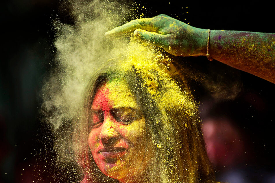 Ein Mann beschmiert das Gesicht einer Frau während der Feierlichkeiten zum Holi-Fest in Mumbai mit farbigem Puder.