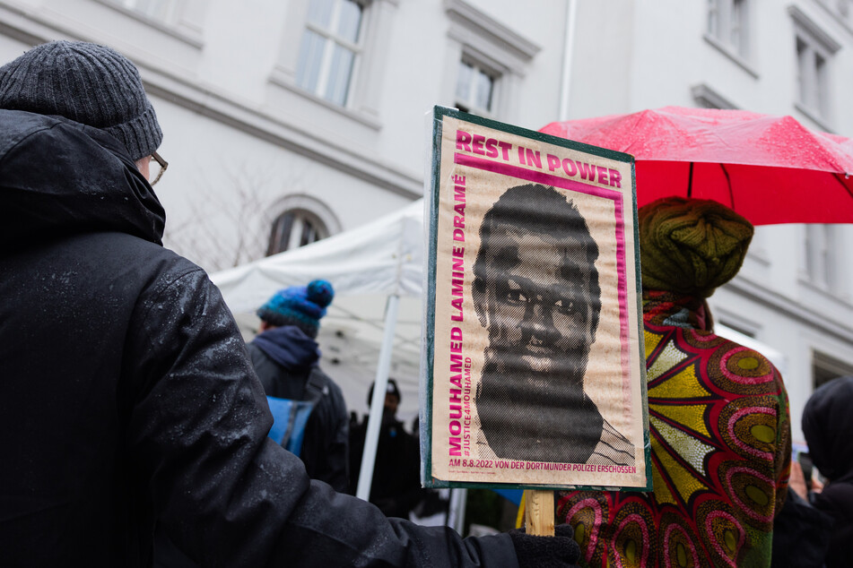 Vor dem Landgericht positionierten sich am Dienstag Demonstranten mit Plakaten, die das Portrait des 16-jährigen Senegalesen Mouhamed Dramé zeigen.