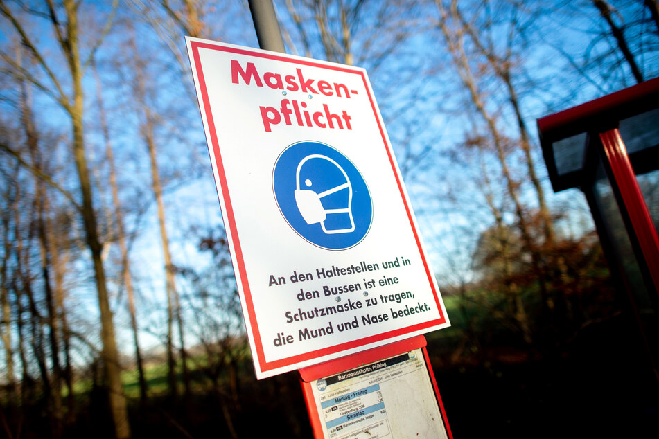 Ein Schild mit der Aufschrift "Maskenpflicht" hängt an einer Bushaltestelle nahe der Ortschaft Bartmannsholte. Die Corona-Infektionen in Deutschland sind auch am Sonntag weiterhin auf einem hohen NIveau.