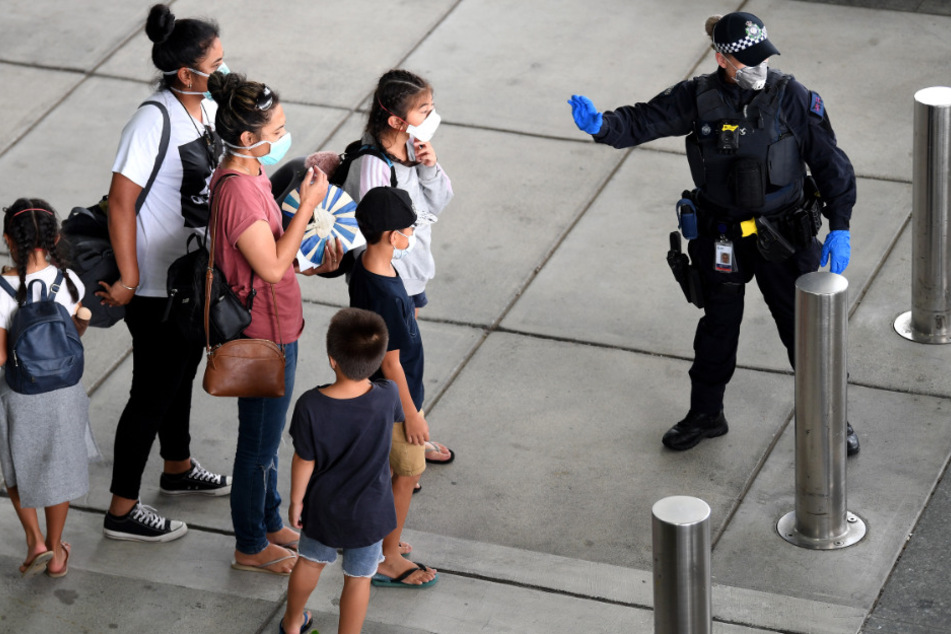 Eine Polizistin mit Mundschutz leitet Passagiere, die mit einem vom US-Außenministerium gecharterten Flugzeug ins Land zurückgeholt wurden.