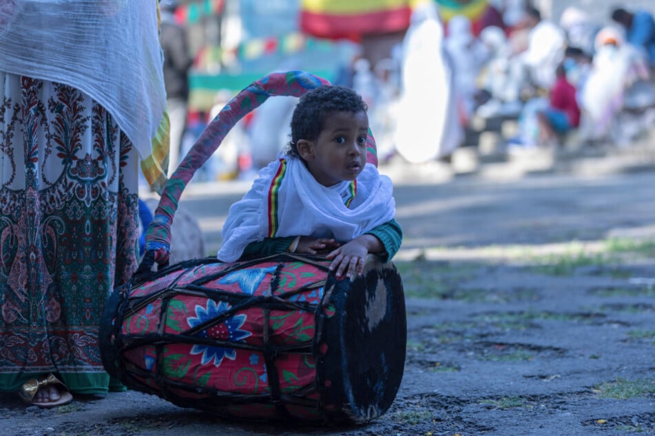 Äthiopien, Addis Abeba: Ein Kind spielt während eines Gottesdienstes zur äthiopischen Weihnacht in der Bale-Wold-Kirche mit einer Trommel, die vom Chor benutzt wird.