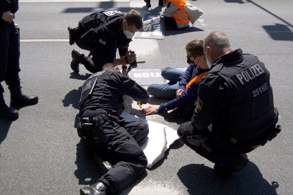 Polizisten kratzen festgeklebte Klimaschützer von Autobahn
