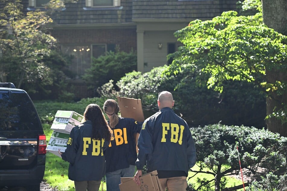 FBI agents carry boxes as they arrive at John Bolton's house, Donald Trump's former national security advisor, after the FBI conducted a court-authorized search at his place on Friday in Bethesda, Maryland.