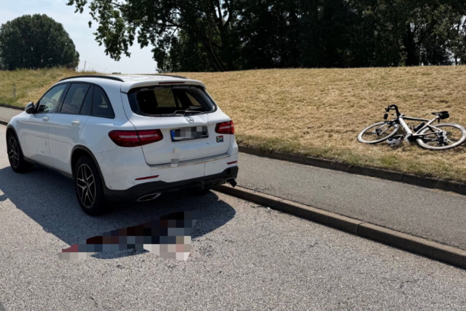 Auf Bildern von der Unfallstelle ist eine große Blutspur in unmittelbarer Nähe des Wagens zu sehen. Das Rennrad liegt neben dem Auto.