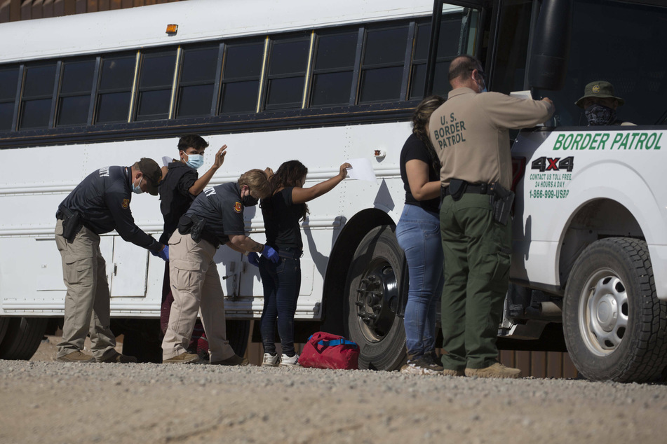 Law enforcement check and search migrants from Columbia after they turned themselves over to authorities at the US-Mexico border.