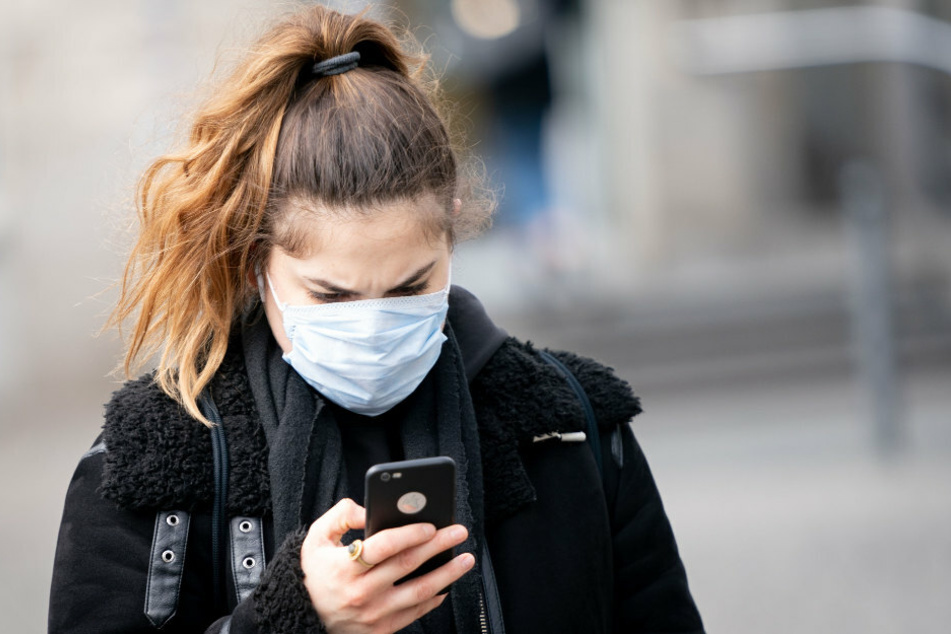 Eine Frau blickt auf dem Alexanderplatz auf ihr Smartphone.