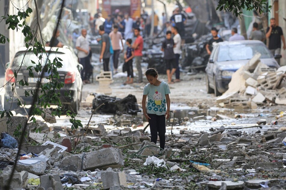 Palestinian girls walks amidst the debris in the Nuseirat refugee camp.