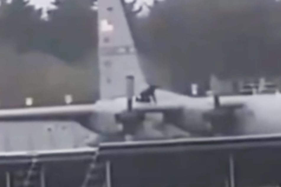 Eine schwarz gekleidete Person schlägt auf das Flugzeug ein.