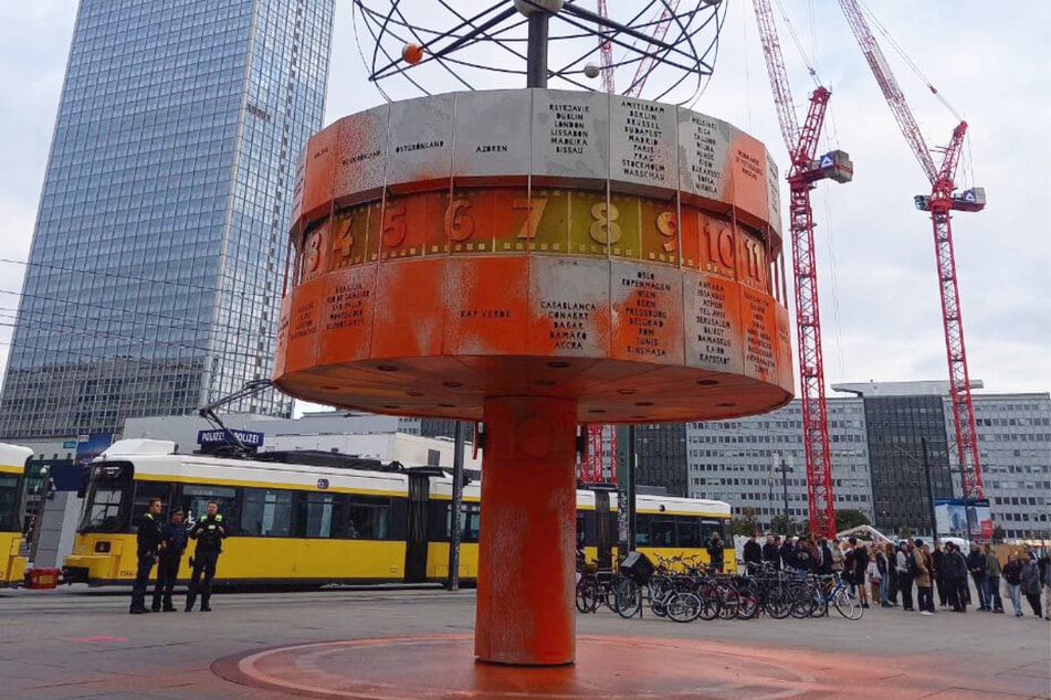 Mehrere Aktivisten der Letzten Generation haben die Weltzeituhr am Alexanderplatz mit oranger Farbe besprüht.
