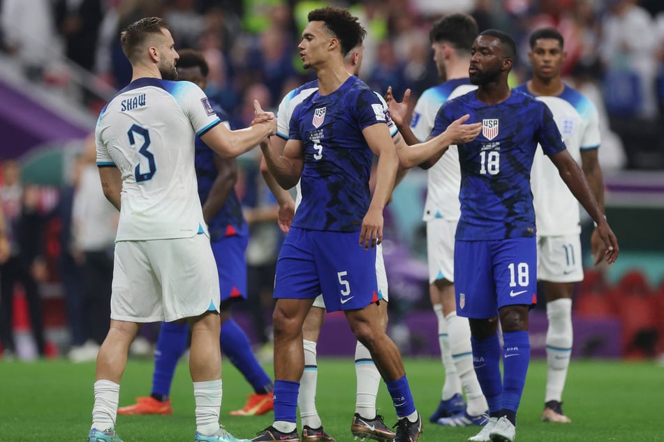 Antonee Robinson and Shaquell Moore shake hands with England's players at the end of the game.