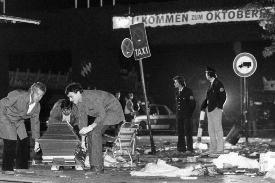 Ein Sarg wird am 26.09.1980 vom verwüsteten Tatort beim Oktoberfest in München (Bayern) weggetragen. (Archivbild)