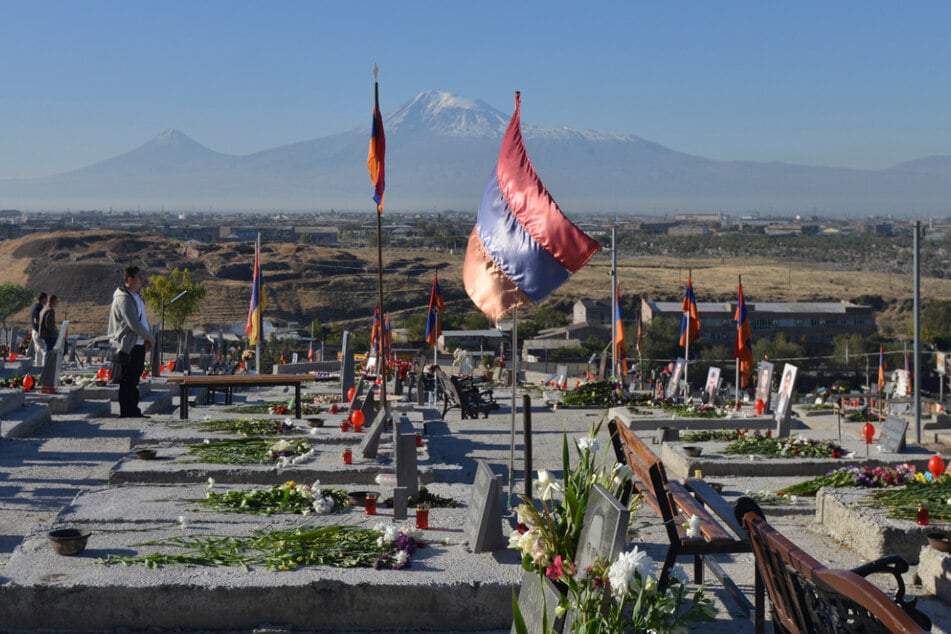 Armenien, Yerevan: Angehörige stehen am Jahrestag des Kriegsbeginns um die umkämpfte Region Berg-Karabach auf einem Soldatenfriedhof.