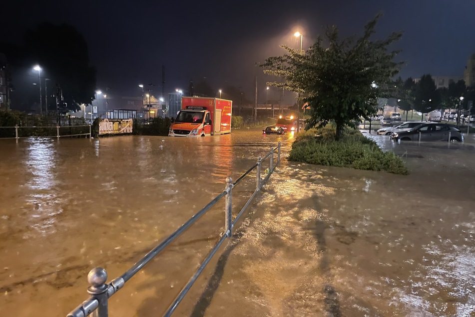 Ein Rettungswagen und Autos stehen in Hagen auf einer überfluteten Straße.