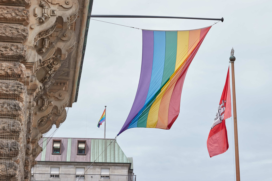 Eine Regenbogenflagge hängt über dem Eingang des Hamburger Rathauses, neben der Fahne der Stadt. Zum Auftakt der Pride Week wurde bei der Aktion "Hamburg zeigt Flagge" die Regenbogenfahne gehisst.