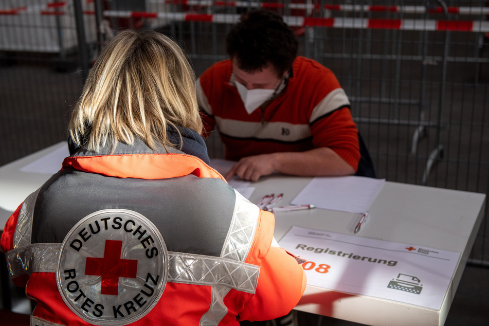 Eine Mitarbeiterin des Deutschen Roten Kreuzes simuliert die Registrierung im Messezentrum. (Symbolbild)
