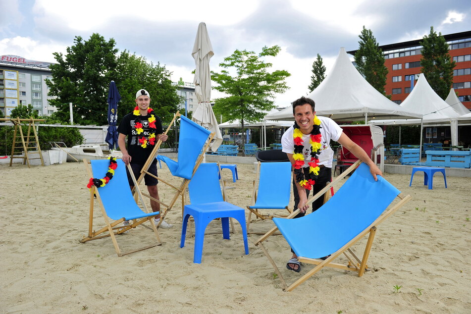 Kevin Weigel (22) und Chef Henrik Bonesky (46, r.) stellen am Uferstrand die Liegestühle für das Public Viewing raus.