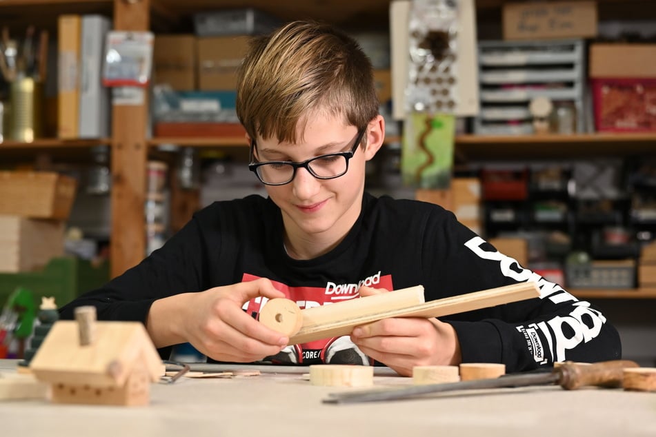 Felix (11) bastelt in der Holzwerkstatt an einer Lokomotive.