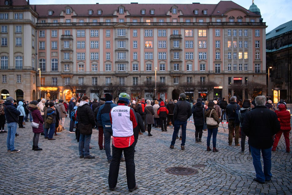 Sachsen, Dresden: Teilnehmer einer Kundgebung der "Querdenker" stehen am Abend auf dem Altmarkt.