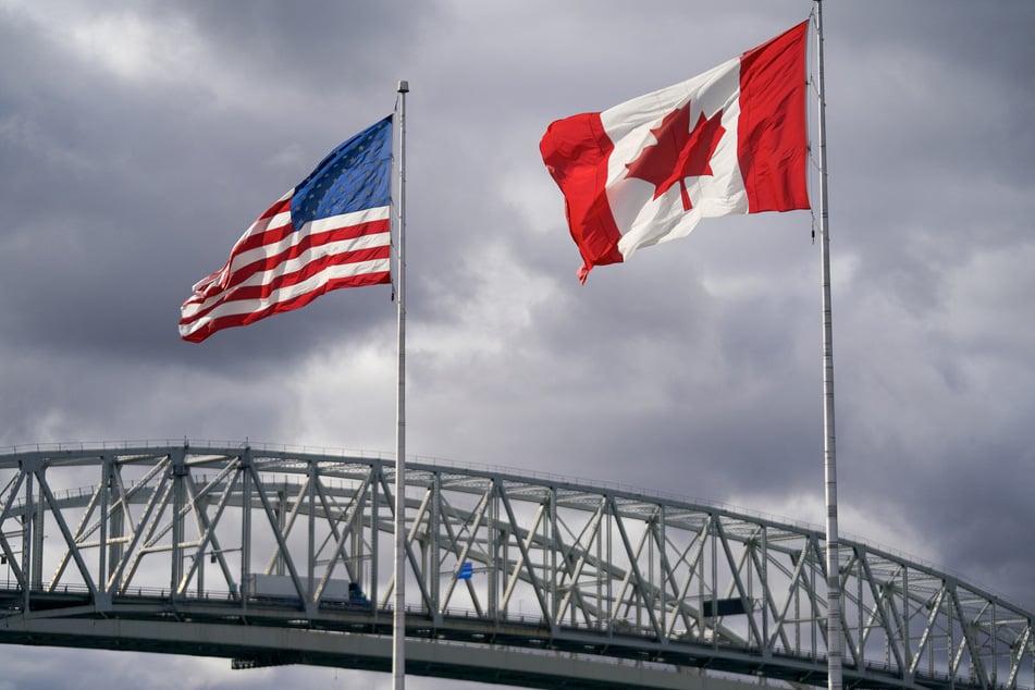 The US and Canada flags flutter next to the Blue Water Bridge border crossing in Point Edward, Ontario.