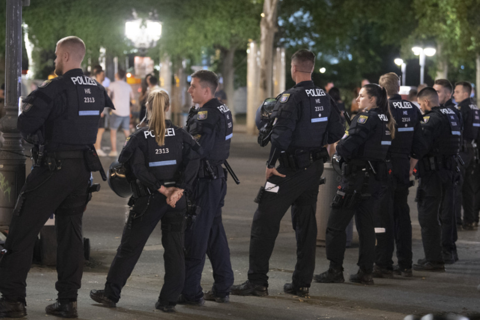 Polizisten stehen abends auf dem Opernplatz.
