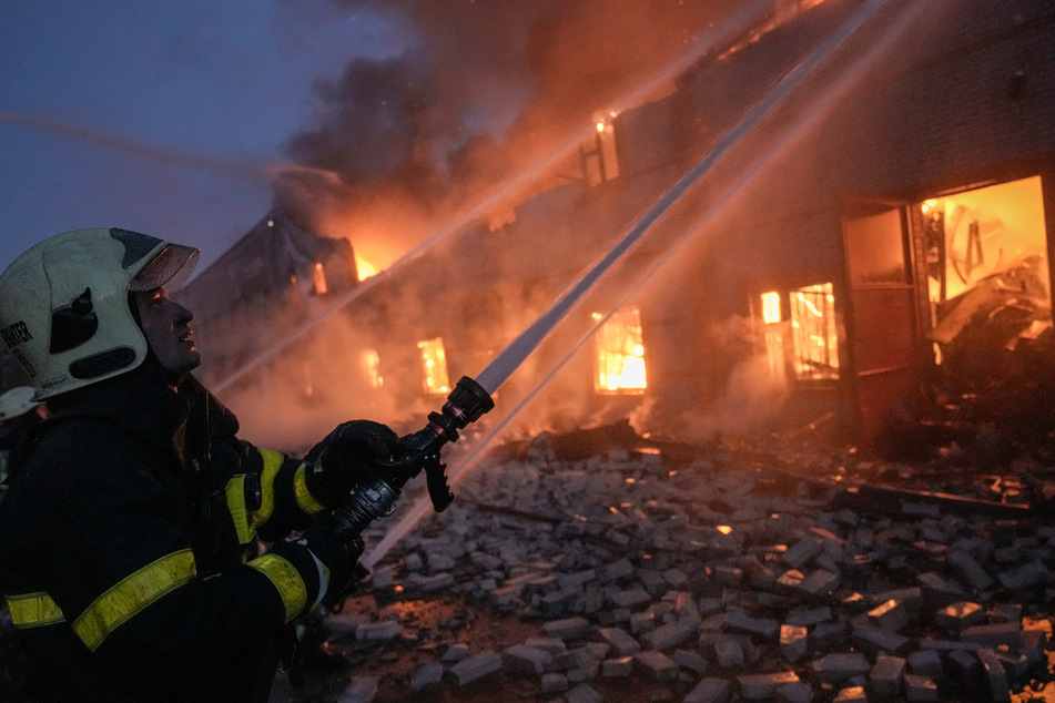 Ukrainische Feuerwehrleute löschen einen Brand in einem Lagerhaus nach einem russischen Bombenanschlag.