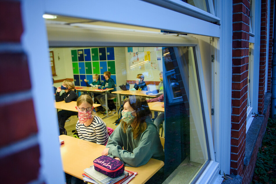 Schülerinnen sitzen während des Unterrichts in ihrem Klassenzimmer und tragen dabei eine Alltagsmaske.