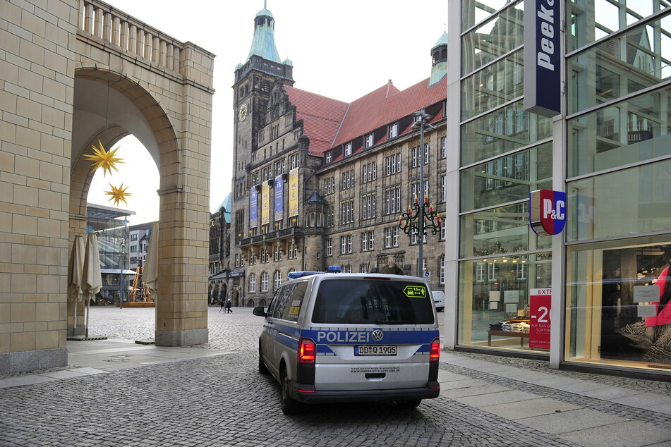 Ein Polizeiwagen fährt auf dem Neumarkt vor dem Rathaus Streife.