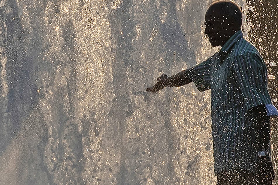 Ein Mann erfrischt sich abends am Wasser des Springbrunnens im Lustgarten.