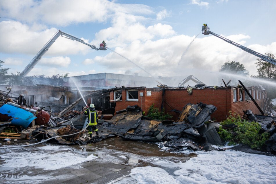 Feuerwehrleute löschen auch am Morgen danach das eingestürzte Schulgebäude.