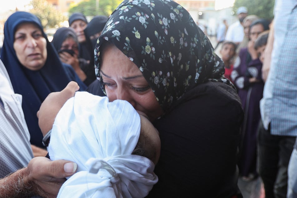 A Palestinian woman kisses the body of a child who was killed in an Israeli strike at Al-Aqsa Martyrs Hospital in Deir Al-Balah in the central Gaza Strip.