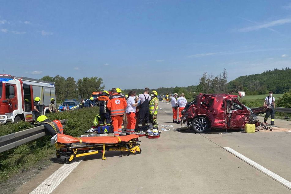 Rettungskräfte stehen neben dem völlig zerstörten Mazda des Geisterfahrers auf der A7.