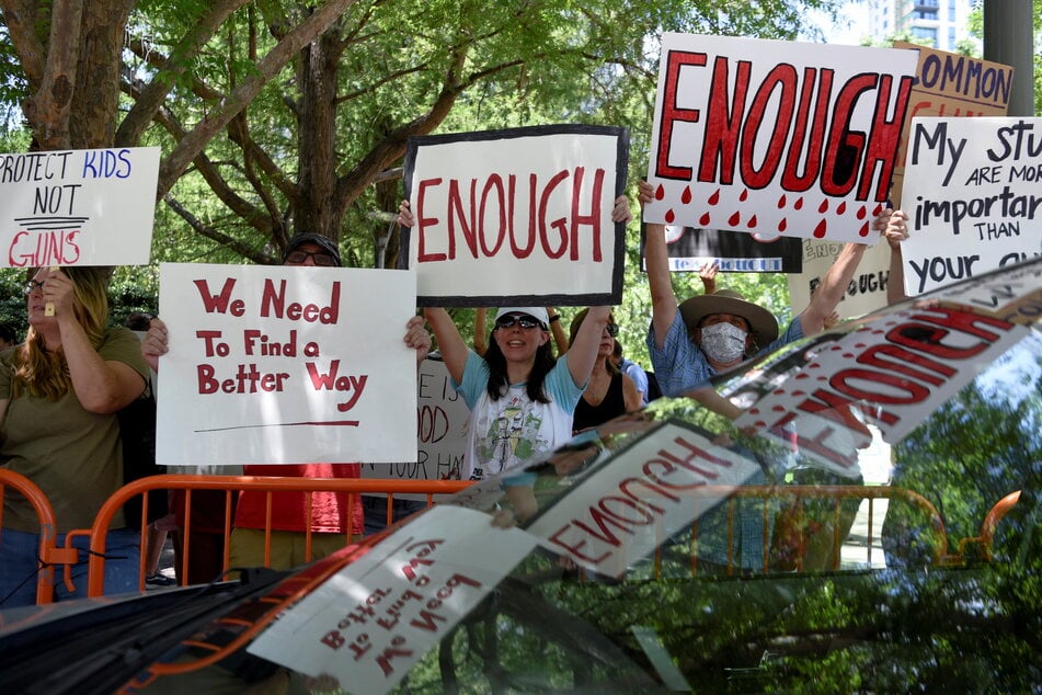 Protesters hold signs calling for gun reform and an end to gun violence.