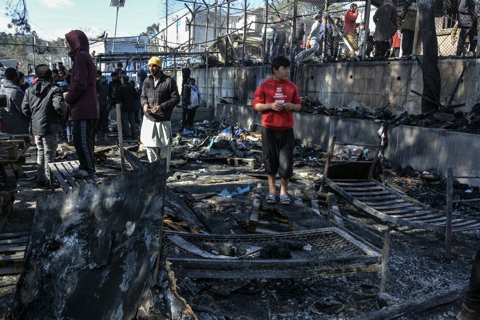 Moria: Migranten stehen auf den abgebrannten Überresten eines Containerhauses. (Archivbild)