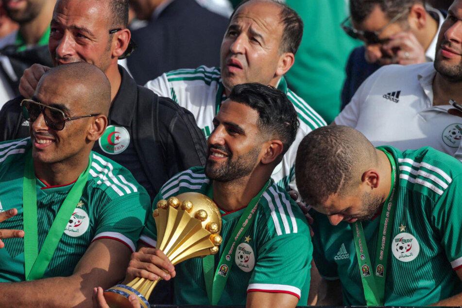 Algerien, Algier: Riyad Mahrez hält die Trophäe während die Spieler der algerischen Fußballnationalmannschaft feiern mit Tausenden von Fans, nachdem sie in Ägypten den Afrika-Cup gewonnen hatten. (Archivbild)