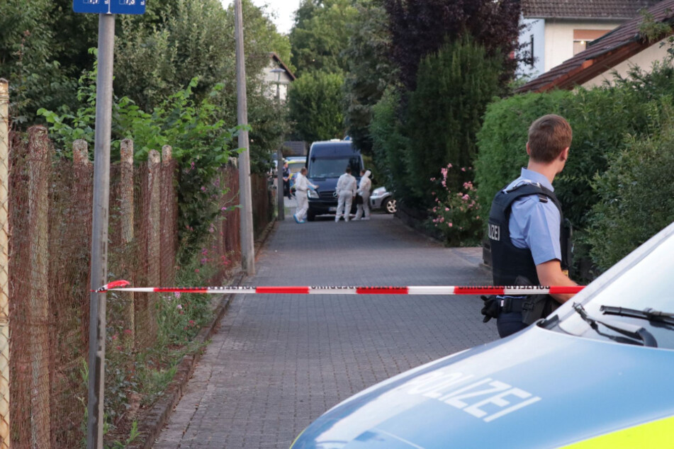 Ermittler der Polizei stehen hinter einer Absperrung. In Erlensee war im Juli 2020 eine Frauenleiche mit Stichverletzungen gefunden worden.