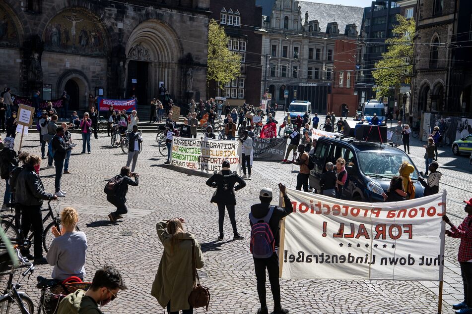 Demonstranten stehen mit Plakaten auf dem Marktplatz. Bei einer Demonstration wird die Schließung der zentralen Erstaufnahmestelle (Zast) an der Lindenstraße gefordert.