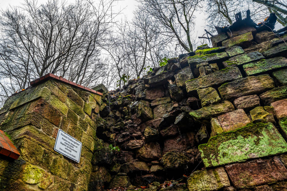 Riesige Brocken liegen lose in der Stützmauer, die vom bewaldeten Hang immer mehr weggedrückt wird.