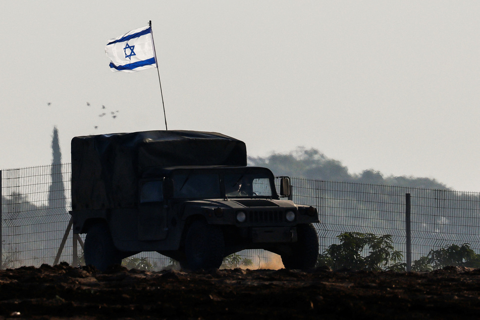 An Israeli flag is seen on a military vehicle as it drives by Israel's border after leaving Gaza during the temporary truce on November 24, 2023.
